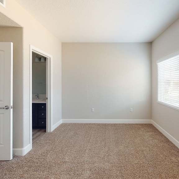 an empty bedroom with a window and a door to a bathroom at heritage landing apartments, chico, 95973