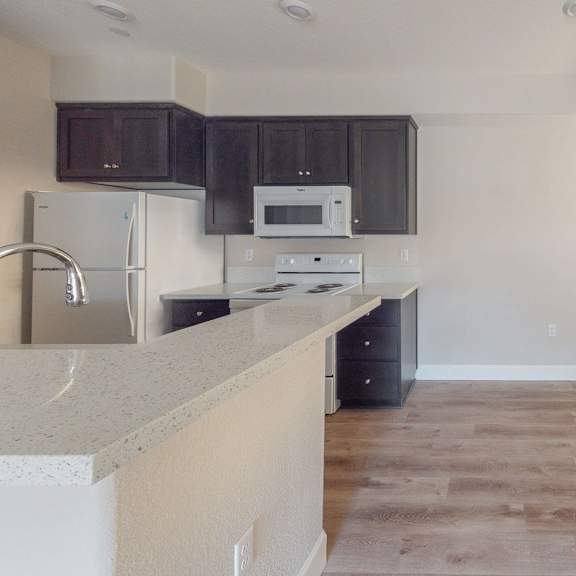 an empty kitchen with dark cabinets and a counter top at heritage landing apartments, chico, 95973