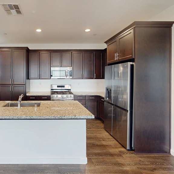 a kitchen with dark brown cabinets and a granite countertop.