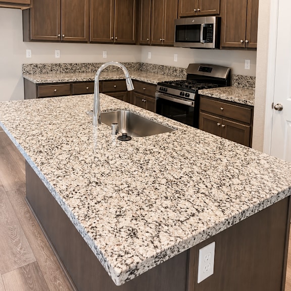 a kitchen with dark brown cabinets and granite countertops.