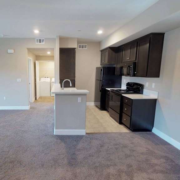 a kitchen and living room with a black stove and at edgewater, pittsburg, ca  