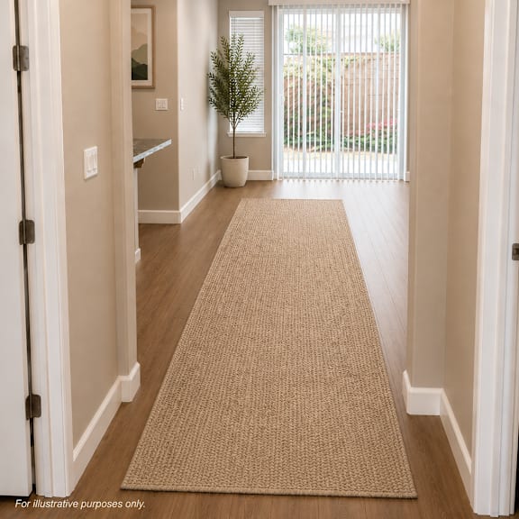 a hallway with a rug on the floor and a plant in a pot.