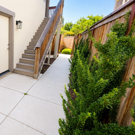 a concrete patio leads to a house with a staircase.