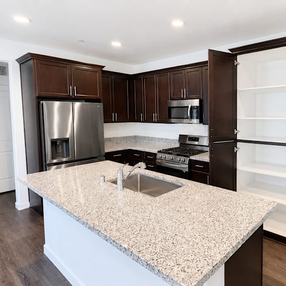 a kitchen with a granite countertop and dark brown cabinets.