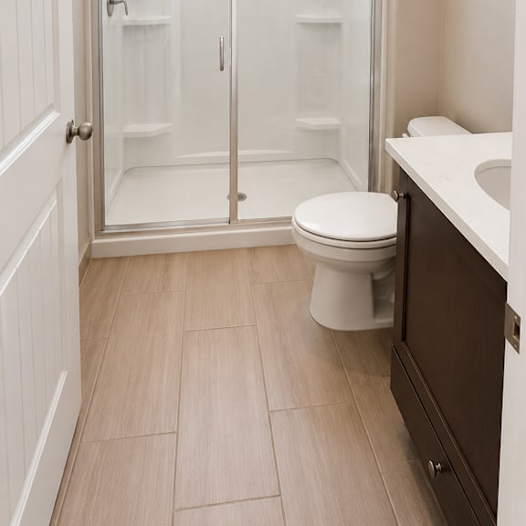 a white toilet in a bathroom with a walk-in shower.