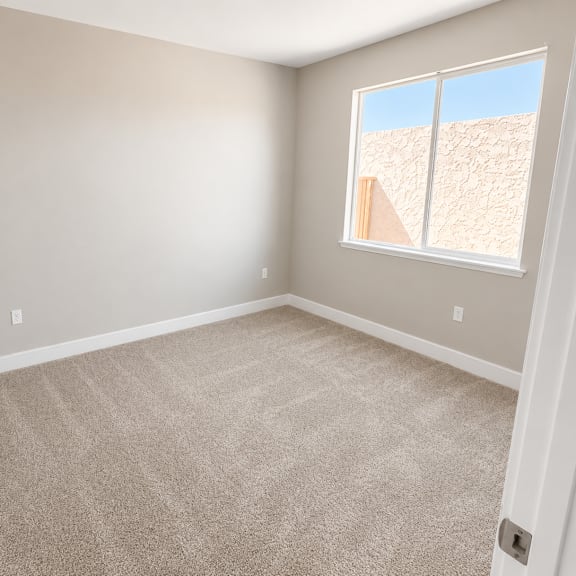 a room with a carpeted floor and a window showing a wall outside.