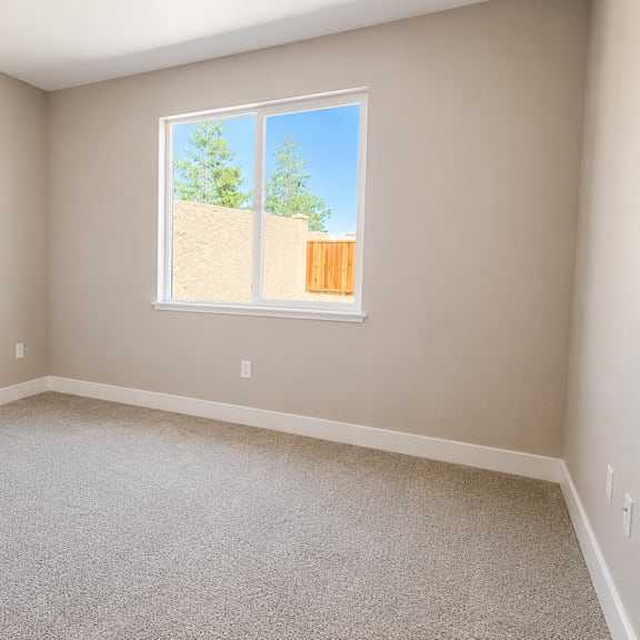 a room with a window showing a view of a fence and trees.
