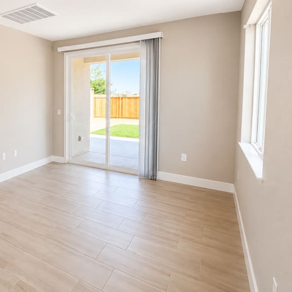 a spacious room with a sliding glass door leading to a backyard.
