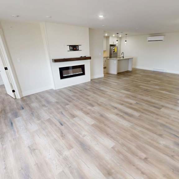 a spacious room with wooden flooring and a fireplace.