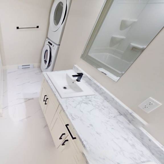 a white bathroom with a washer and dryer built into the cabinetry.