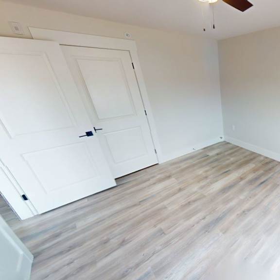 a room with a white door and wooden flooring.