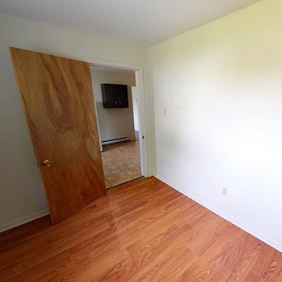 a room with a wooden floor and a door leading to another room.