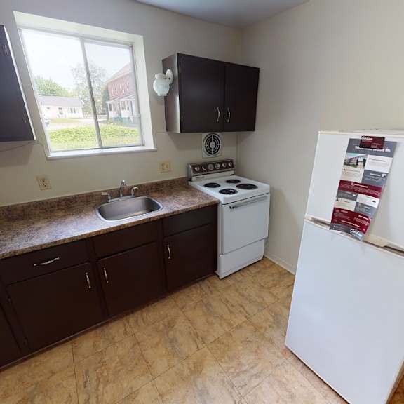 a kitchen with a white fridge and a window.