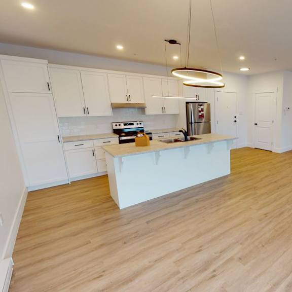 a kitchen with white cabinets and a wooden floor.