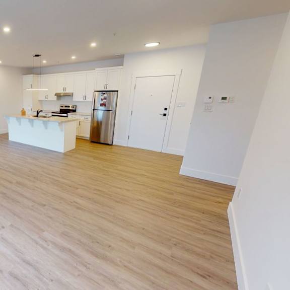 a spacious kitchen with wooden flooring and white walls.