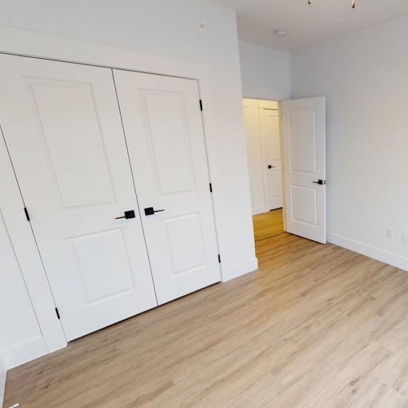 a room with white walls and wooden flooring with two doors.