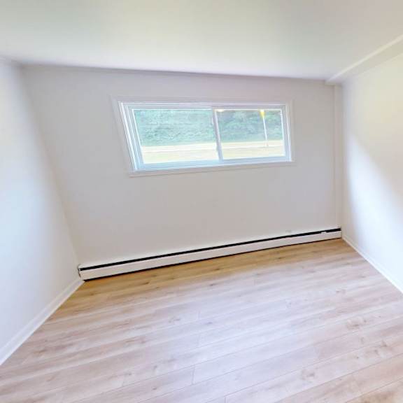 a room with a window and wooden flooring.