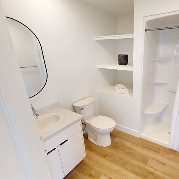 a white bathroom with a toilet, sink, and shower.