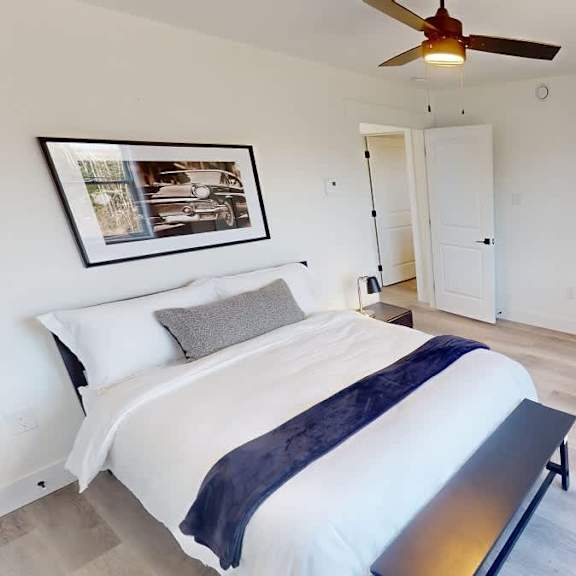 a bedroom with a bed, a ceiling fan, and a picture on the wall.