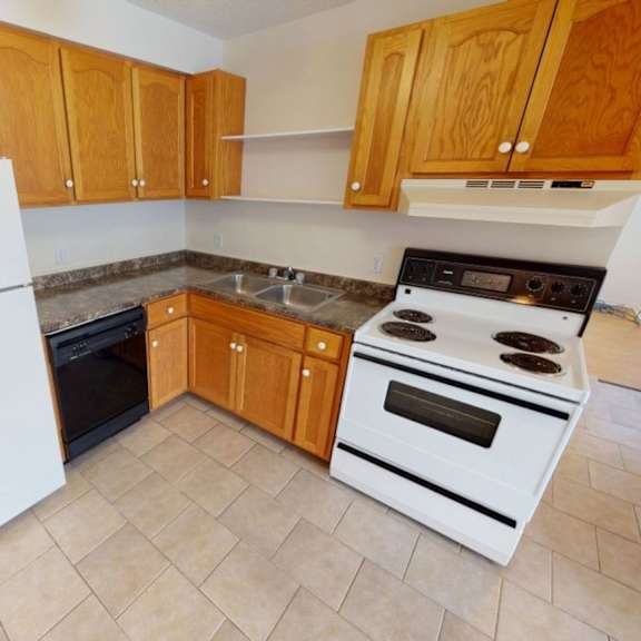 a kitchen with a white fridge, white stove, and wooden cabinets.
