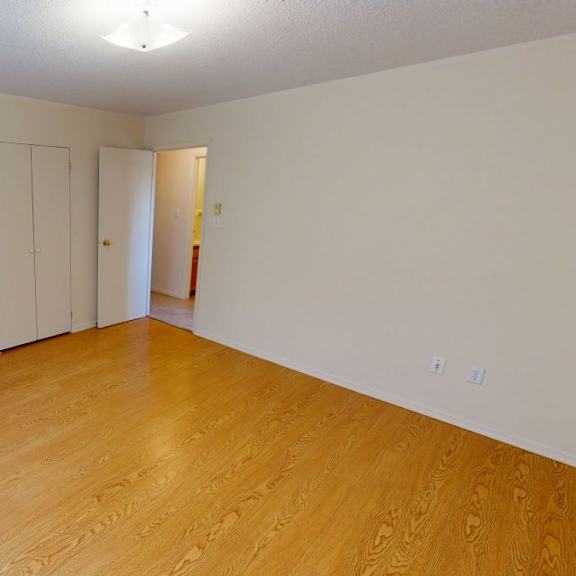 a room with wooden floors and white walls with a door and a cabinet.