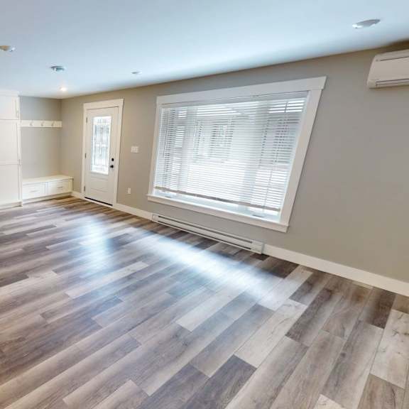 a room with wooden flooring and a window with blinds.