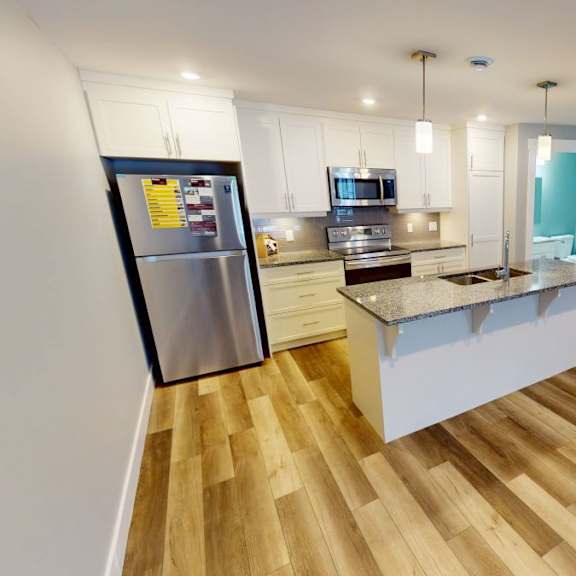 a kitchen with a refrigerator, cabinets, and a countertop.