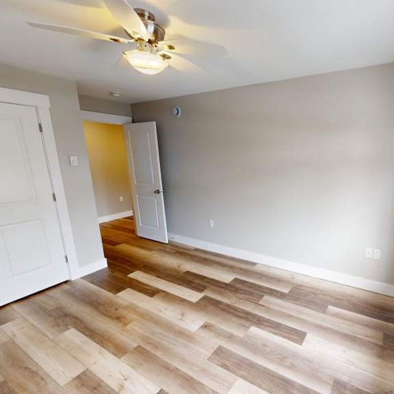 a room with a ceiling fan and wooden flooring.