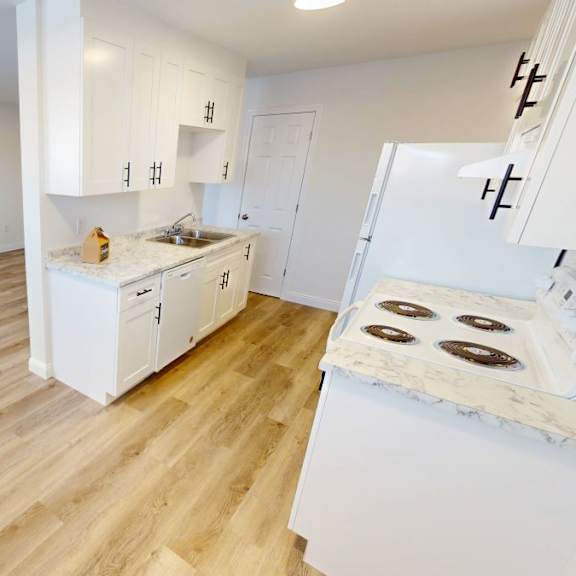 a kitchen with white cabinets and a wooden floor.