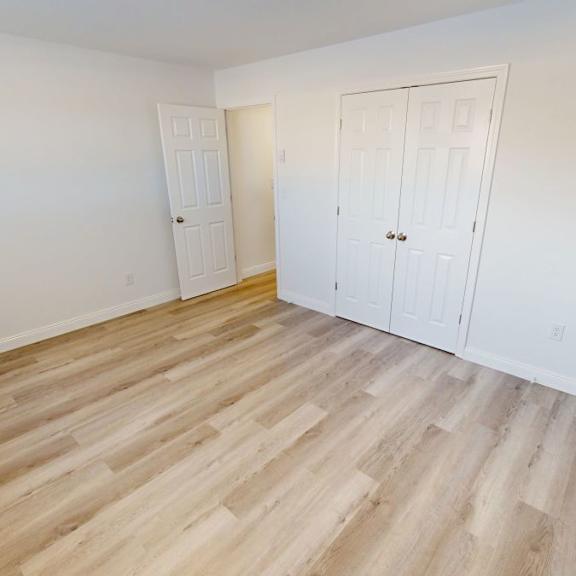a room with wooden flooring and two white doors.