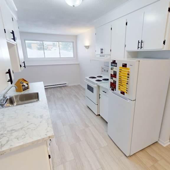 a kitchen with white cabinets and a marble countertop.