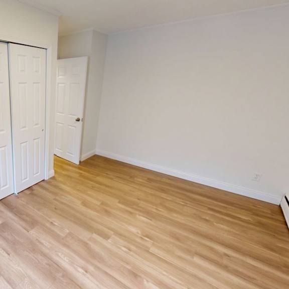 a room with a white door and wooden flooring.