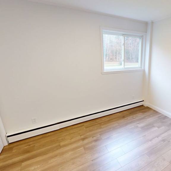 a room with a window and wooden flooring.