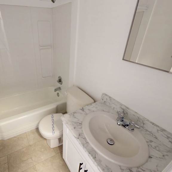 a white bathroom with a marble sink and a toilet.