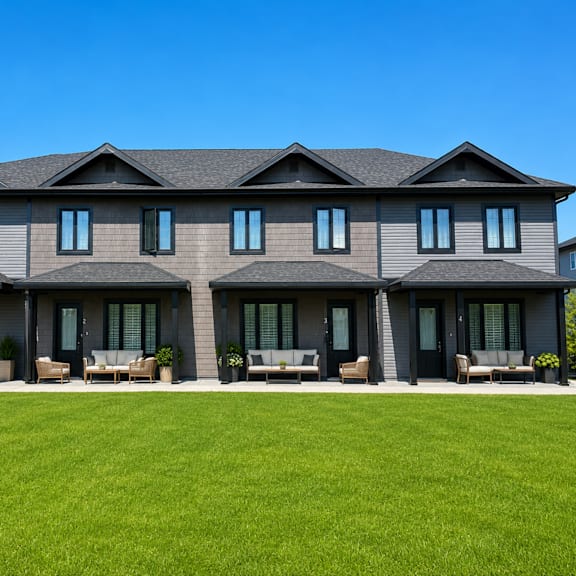 a large house with a grey roof and a green lawn in front.