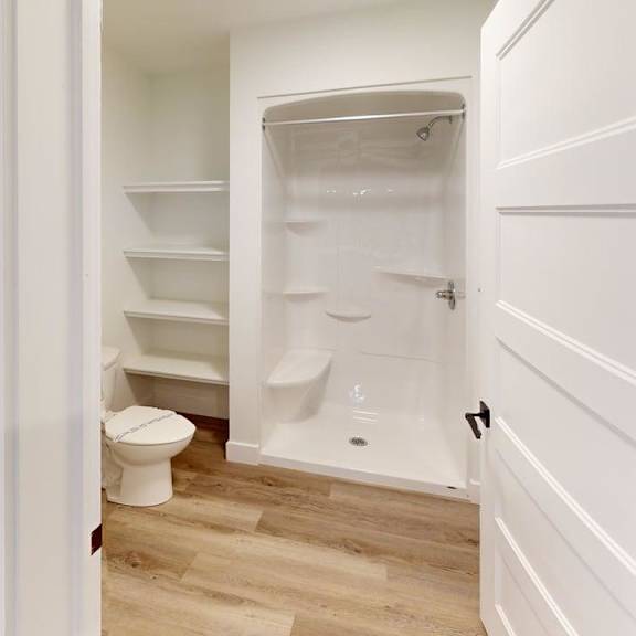 a white toilet is in a small bathroom with a walk-in shower.