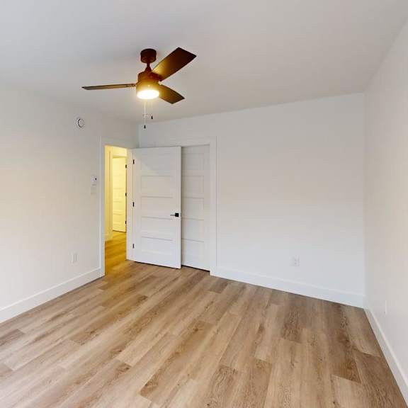 a room with a ceiling fan and wooden flooring.