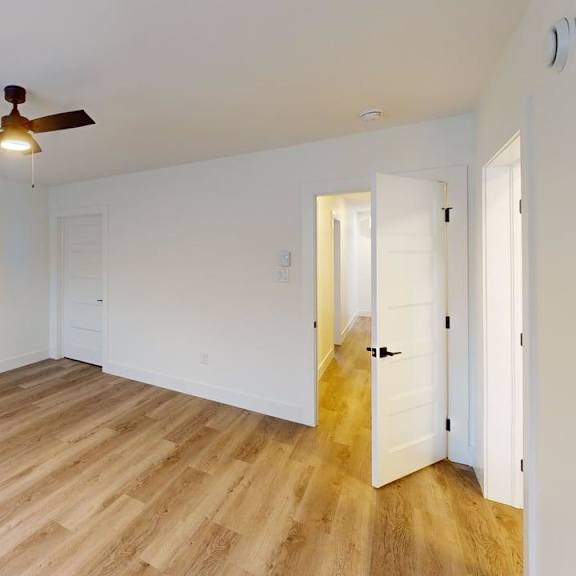 a room with a ceiling fan and wooden flooring.