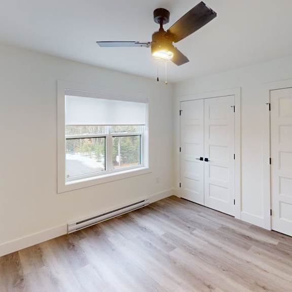a room with a ceiling fan and a window with blinds.