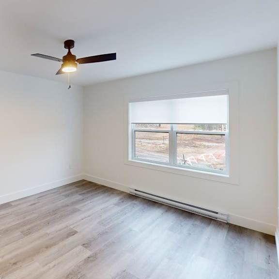 a room with a ceiling fan and a window overlooking a construction site.