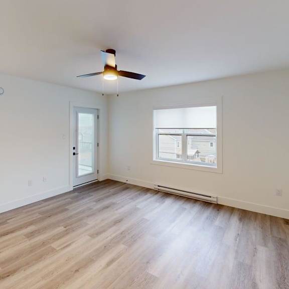 a room with a ceiling fan and a window with a view of other buildings.