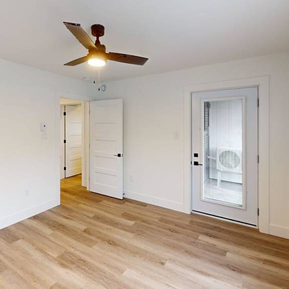 a room with a ceiling fan and wooden flooring.