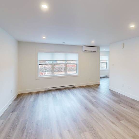 a room with wooden flooring and a window with blinds.