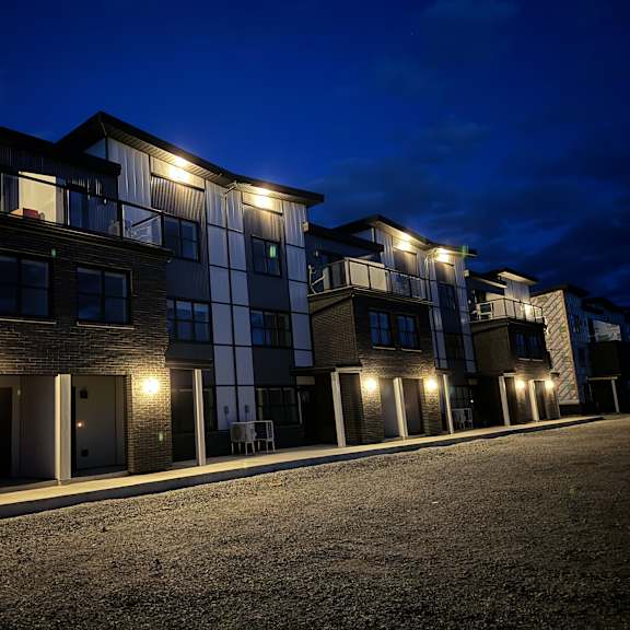 a row of modern townhouses are lit up at night.