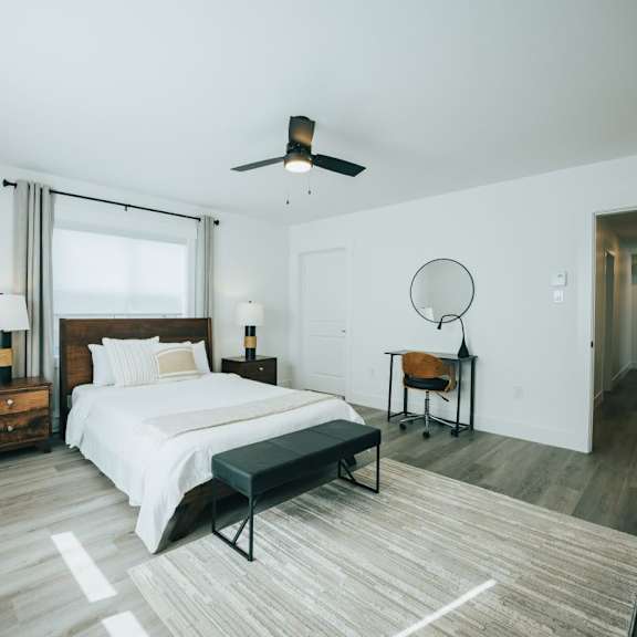 a bedroom with a bed, a chair, and a ceiling fan.