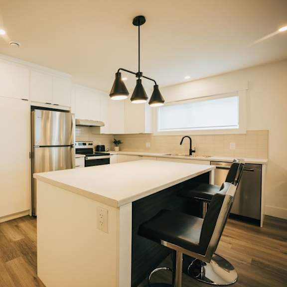 a kitchen with a white counter and a black chair.