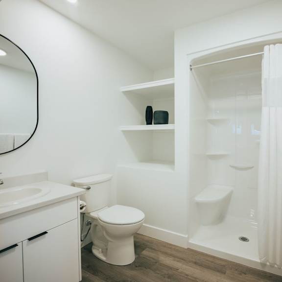 a white bathroom with a toilet, sink, and shower.
