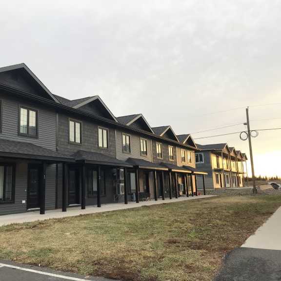 a row of modern houses with a car parked in front of the first house.