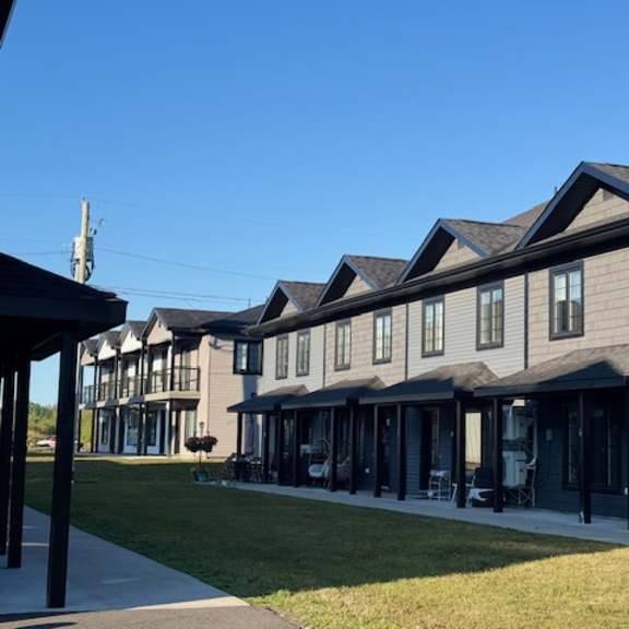 a row of houses with dark grey siding and white trim.