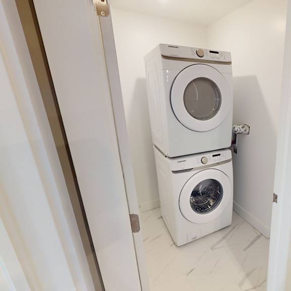 a white washing machine is in a small, white-walled laundry room.